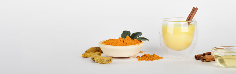 Hot healthy drink. Turmeric, golden milk with turmeric root, powder, honey and cinnamon on white background. Copy space. Alternative medicine concept