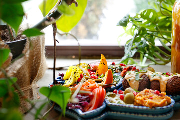 Falafel with vegetables, a colorful vegetarian dish. A healthy vegan diet.
Tasty colorful healthy dish served on a background of green plants. Suggestion to serve the dish. Culinary photography.