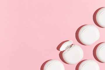 Closed and one open white box with dental floss in hard light on a pink background copy space for...
