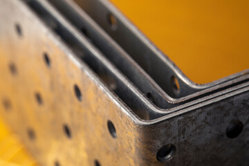 Stack of construction perforated steel angle brackets close up. Low depth of field photography