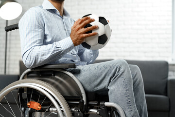 Invalid or disabled man sitting on wheelchair and holding soccer ball