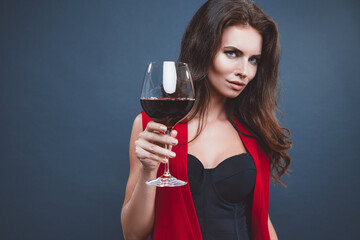 Woman with bright makeup, hairstyle wearing red dress posing with glass of vine over dark background, isolate.