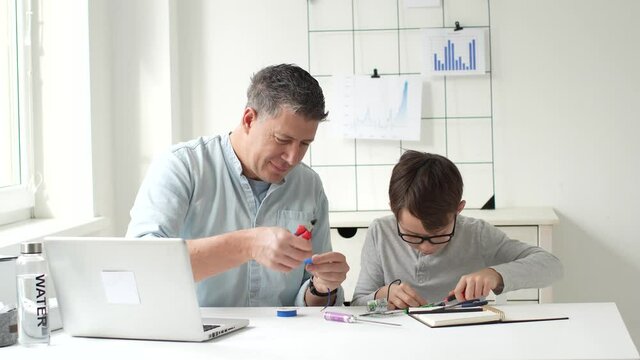 father and son tinker with electrical switches and sockets at the table
