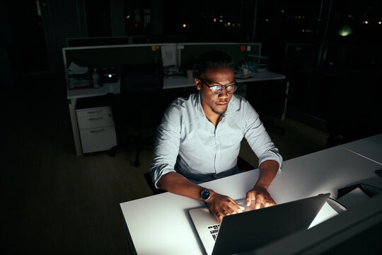 African young business man working at the laptop till late at night in dark office