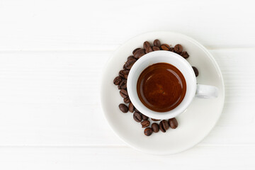 Cup of espresso coffee and coffee beans on white surface