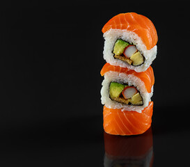 Balancing fresh sushi rolls on a black background with reflection. Japanese kitchen, restaurant, copy space. © Jane Vershinin