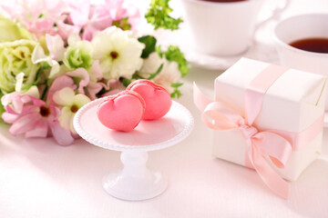 Fototapeta na wymiar Heart shaped macarons with Beautiful bouquet of spring flowers and gift box on the table. Valentine or mothers day concept ピンクのハート型マカロン スプリングブーケ　プレゼント