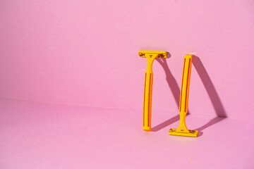 Yellow disposable razors on pink background, studio shot