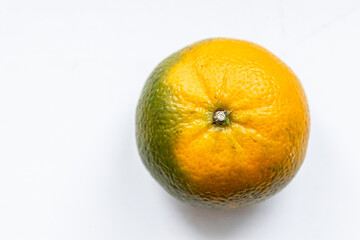 One unripe orange green matte tangerine on white background. Top view. Close-up, macro. Right location. Template