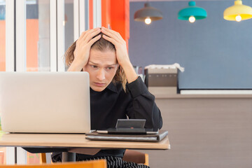 Frustrated man looking at laptop holding his hands to his head, Tired and worried business man at workplace