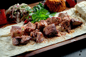 Grilled beef fillet with bulgur and vegetables garnished on a wooden board. Turkish kebab. Close up, selective focus
