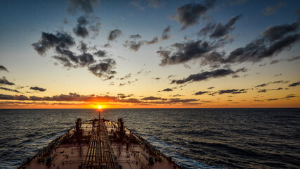 Large crude oil tanker is proceeding to sunset horizon by ocean - view from navigation bridge