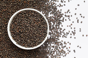 Close up of Organic Black Gram (Vigna mungo) on a ceramic white bowl with the gradient background of whole black urad. Top view 