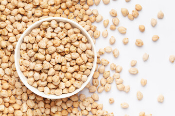 Close up of Organic small chhole chana or Kabuli chana (Cicer arietinum) on a ceramic white bowl with the gradient background of whole white Bengal gram dal. Top view 
