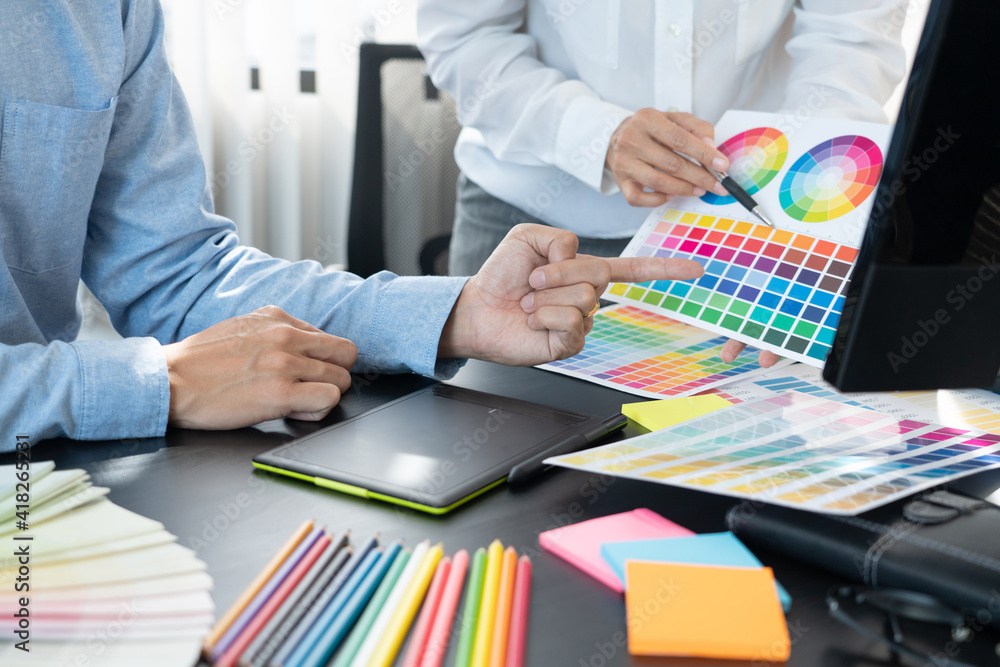 Poster graphic designer team working on web design using color swatches editing artwork using tablet and a 