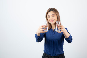 Beautiful woman in blue blouse holding glass of water on white background