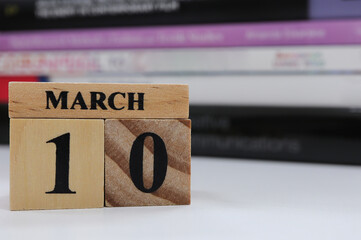 Day 10 of March month, Wooden calendar and stack of books on the table.