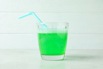 Soda is poured into a glass against white wooden background
