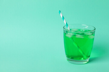 Glass of green soda on mint background