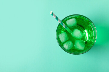 Glass of green soda on mint background