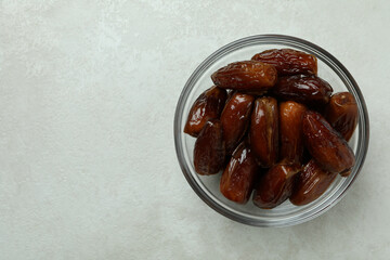 Glass bowl of dates on white textured background