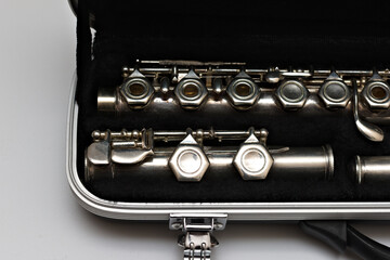 Obraz premium Partial view of a shiny disassembled silver flute in a black case. Studio photo on white background