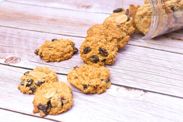Butter cookies with black raisin were poured on the wood table from plastic bottle.