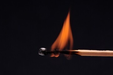 Allumette en feu en gros plan sur fond noir