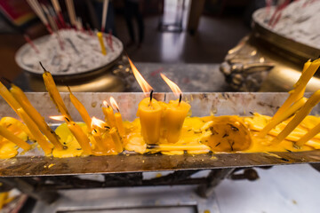 Close up of burning yellow candles In Temple