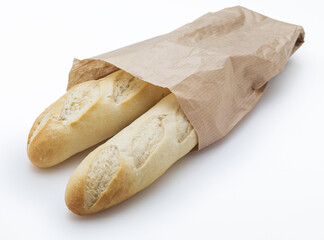 Crisp loaves of freshly made white bread in a paper bag. Isolated on white background.