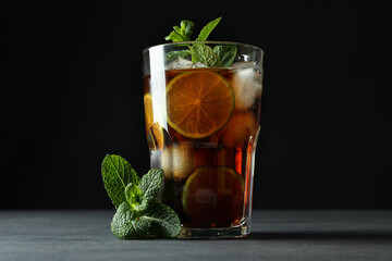 Glass of Cuba Libre and mint against dark background