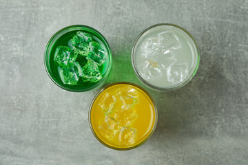 Glasses of different soda on gray background