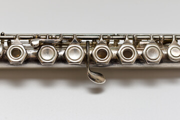 Obraz premium Silver flute with keys on a white sheet