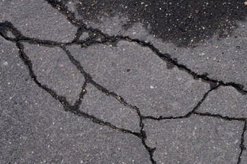Obraz premium Abstract background of old cracked asphalt with wet traces of cars