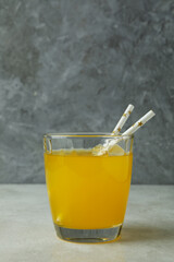 Fototapeta na wymiar Glass of orange soda on white textured table against gray background