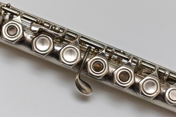 Fototapeta premium A shiny silver flute lies diagonally on a white sheet