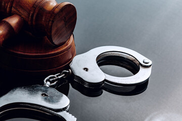 Judge mallet and handcuffs on black background