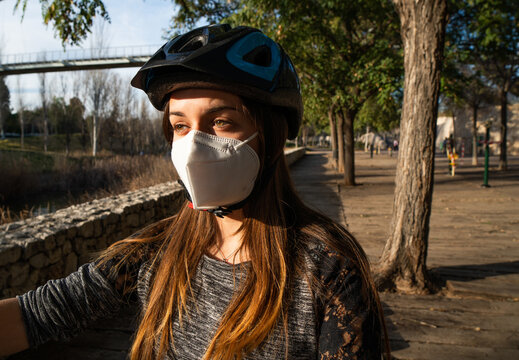 Girl with mask and bicycle helmet in the park.