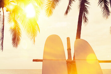 Surfboard and palm tree on beach background.