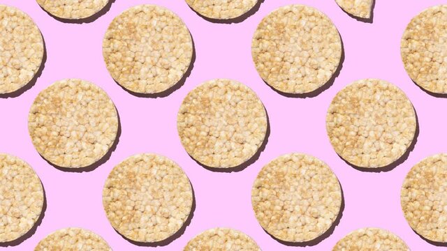Stop motion animation pattern round gluten-free rice crispbread changing from whole to bitten on pink background