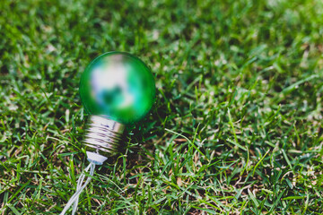 green light bulb on perfect green grass lawn, ecology and sustainability