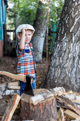 the child cuts wood with an axe and throws it into a pile