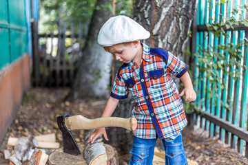the child cuts wood with an axe and throws it into a pile
