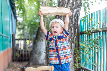 the child cuts wood with an axe and throws it into a pile