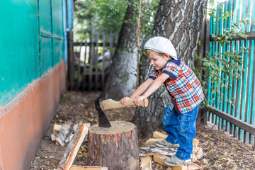 the child cuts wood with an axe and throws it into a pile