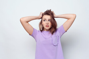 Fototapeta premium Portrait of girl in casual t shirt in panic grabbing her head in fear or frustration. Stress and mental health