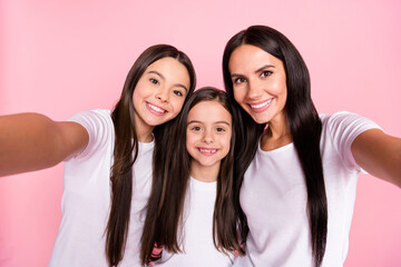 Photo portrait of smiling happy family mother and daughters talking selfie together isolated pastel pink color background