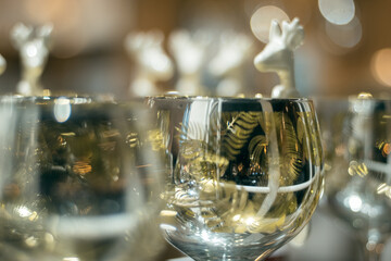 Closeup of a white ceramic deer spoons design hanging on a glass with beautiful soft bokeh in the background, copy space festive image