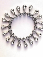 Silver jewerly, bracelet with drop-shaped diamonds hanging around it. 