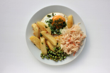 Healthy breakfast with potato, fried egg, green peas and parsley, pickled cabbage salad on white background.  Top view, copy space